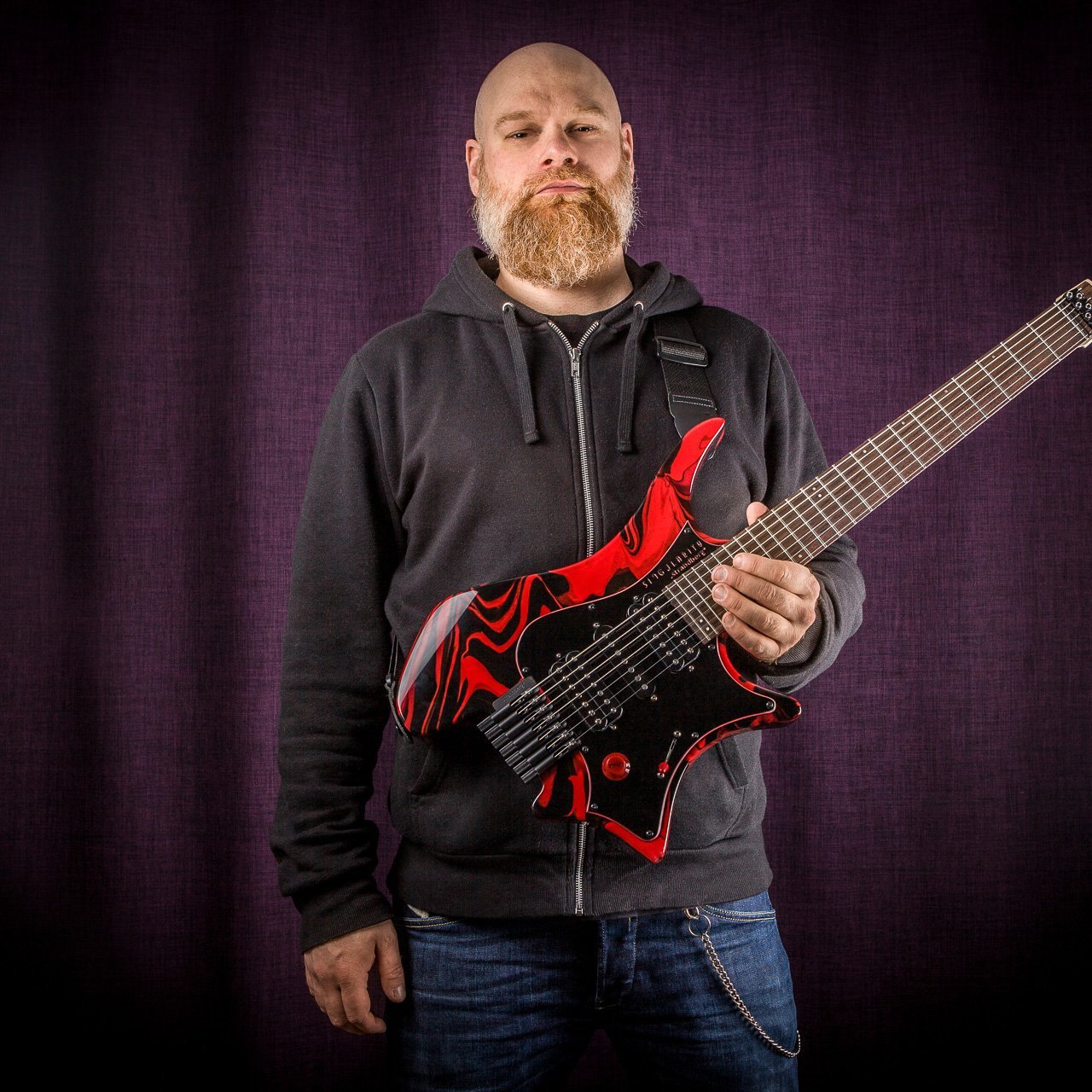 Per Nilsson holding Headless Guitar Boden Singularity 7-string Red Swirl