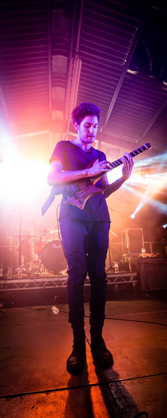 Plini on stage with his signature guitar