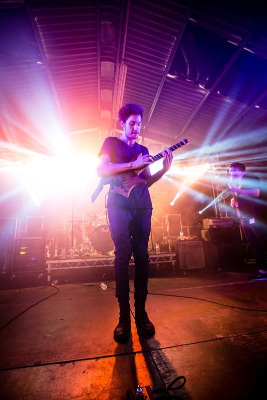 Plini on stage with his signature headless guitar