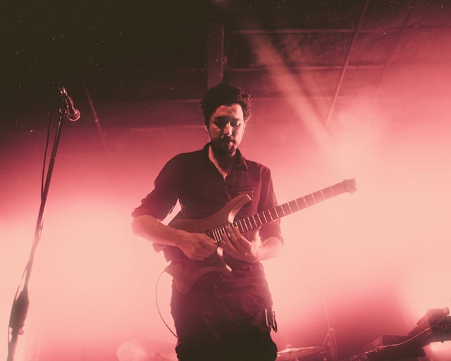 Plini on stage with his signature headless guitar