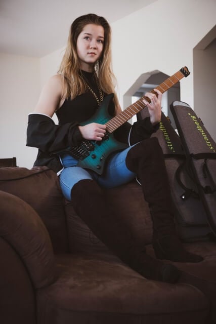 Erin Coburn on sofa holding strandberg headless guitar